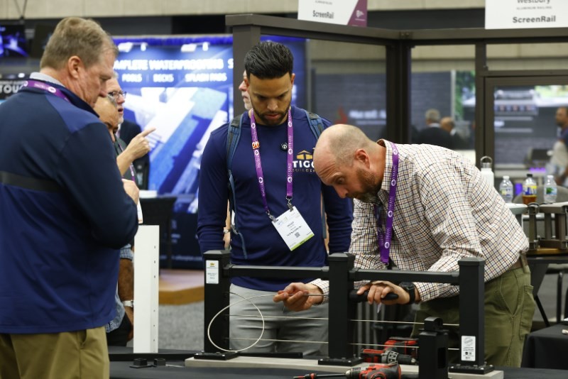 Deck Expo attendees examining railing at an outdoor living and decking exhibitor booth
