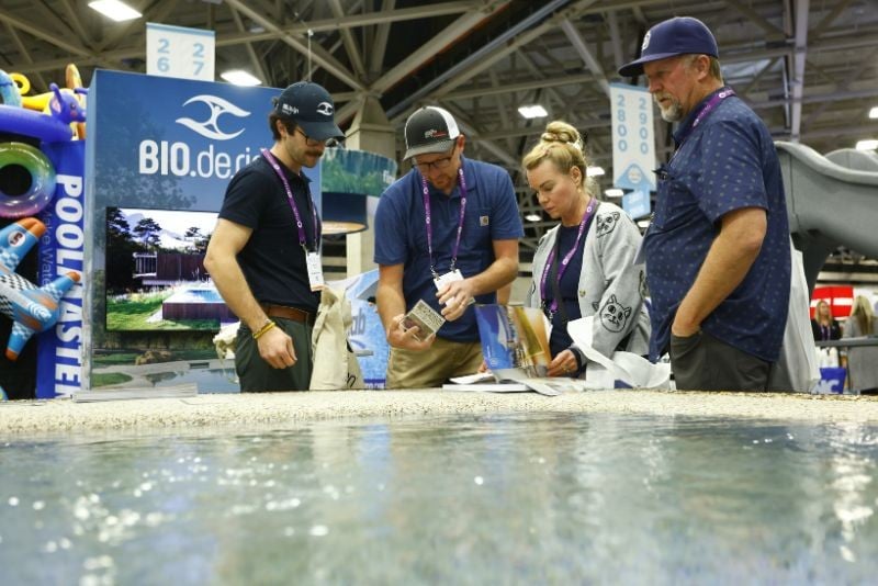 Pool builders looking at a product on the PSP Expo exhibit hall floor